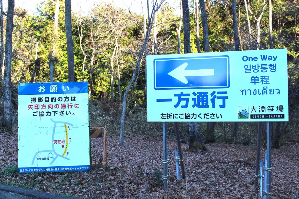 大淵笹場の入口に設置された「一方通行」の案内看板。撮影目的の車両に対して左折通行とルート厳守を求める注意書き。
