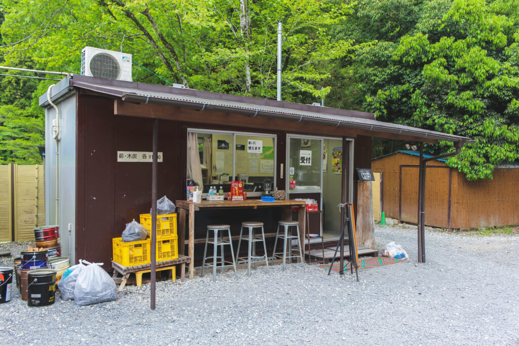 蜂花苑キャンプ場の受付兼売店、薪や日用品が並ぶオープンカウンター