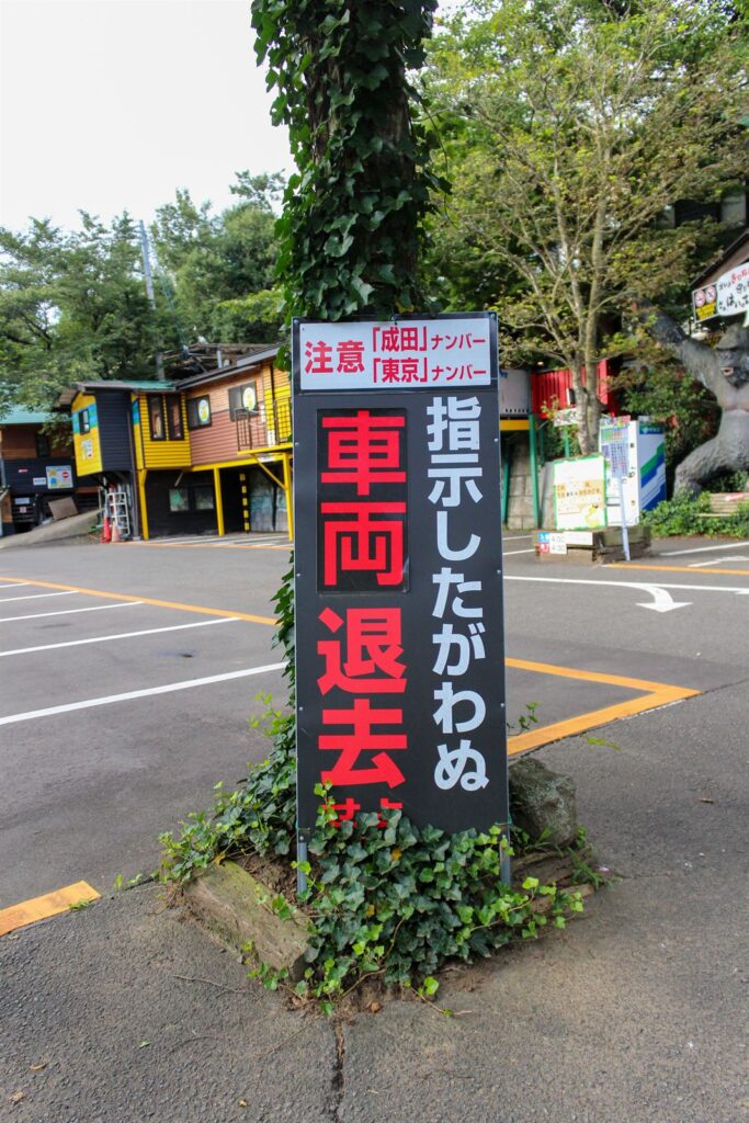駐車場に立つ、指示に従わない車両は退去を求める注意看板